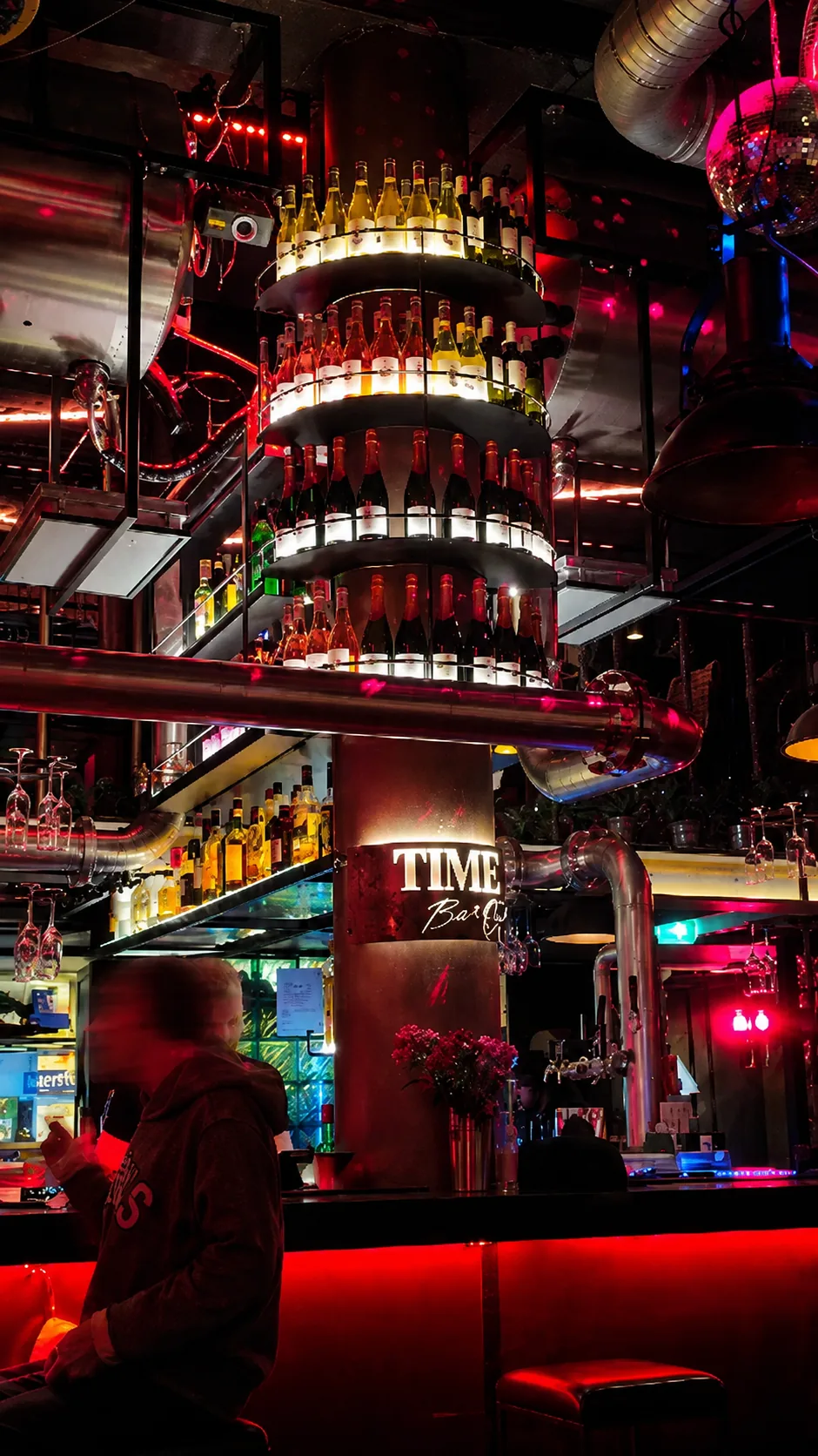 TIME:s upplysta flasktorn, metallrör och spegelkulor ovanför baren